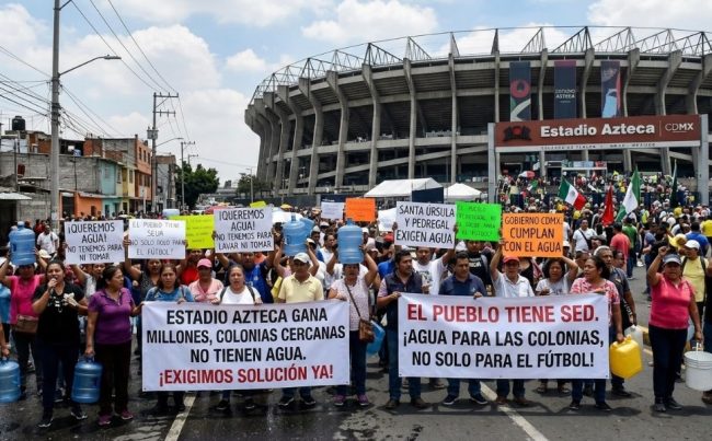 A los habitantes de la colonia Pedregal de Santa Úrsula, junto al estadio Azteca, no les han hecho justicia cuatro Mundiales de Futbol, ni los gobiernos del Partido Revolucionario Institucional, Partido de la Revolución Democrática, ni el Movimiento de Regeneración Nacional. Sus problemas de escasez de agua persisten. IMAGEN: Recreación de protestas en el Estadio Azteca con inteligencia artificial de Gemini